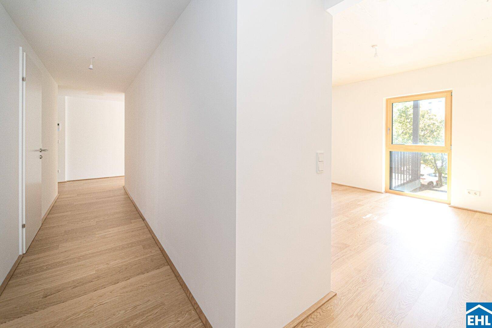 Heller Flur mit Holzboden, der zu den verschiedenen Zimmern der modernen Wohnung führt.