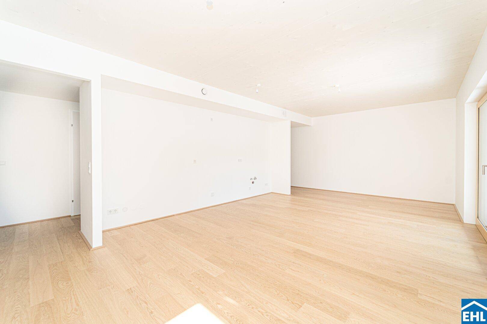 Geräumiger, heller Raum mit Holzboden und weißen Wänden, bereit für die Einrichtung eines Wohnbereichs.