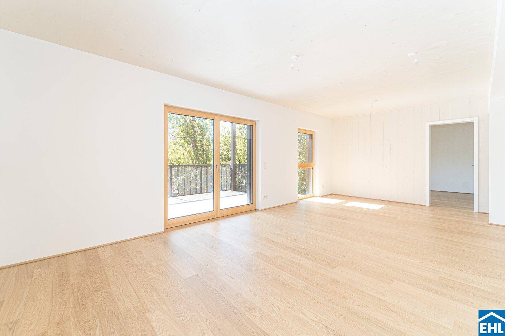 Helles, leeres Wohnzimmer mit Holzboden und Zugang zu einem Balkon, ideal für individuelle Gestaltung.