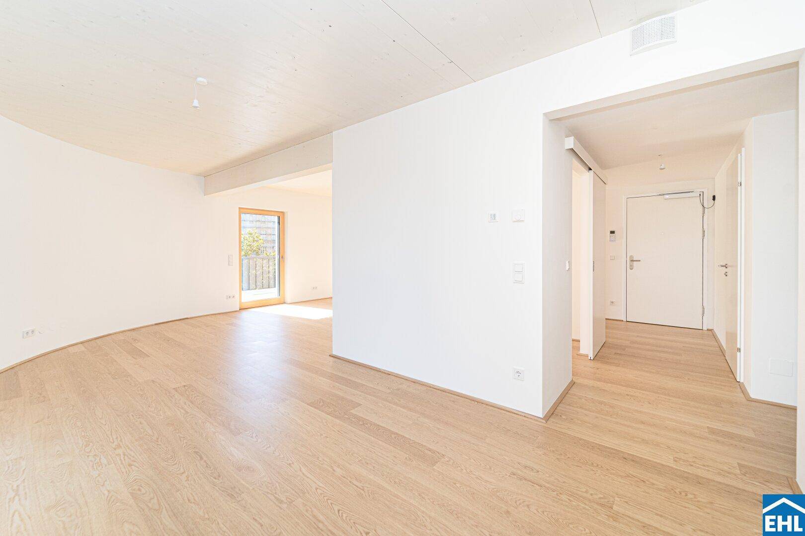 Heller Eingangsbereich mit Holzboden, weißen Wänden und offenem Übergang zu den Wohnräumen.