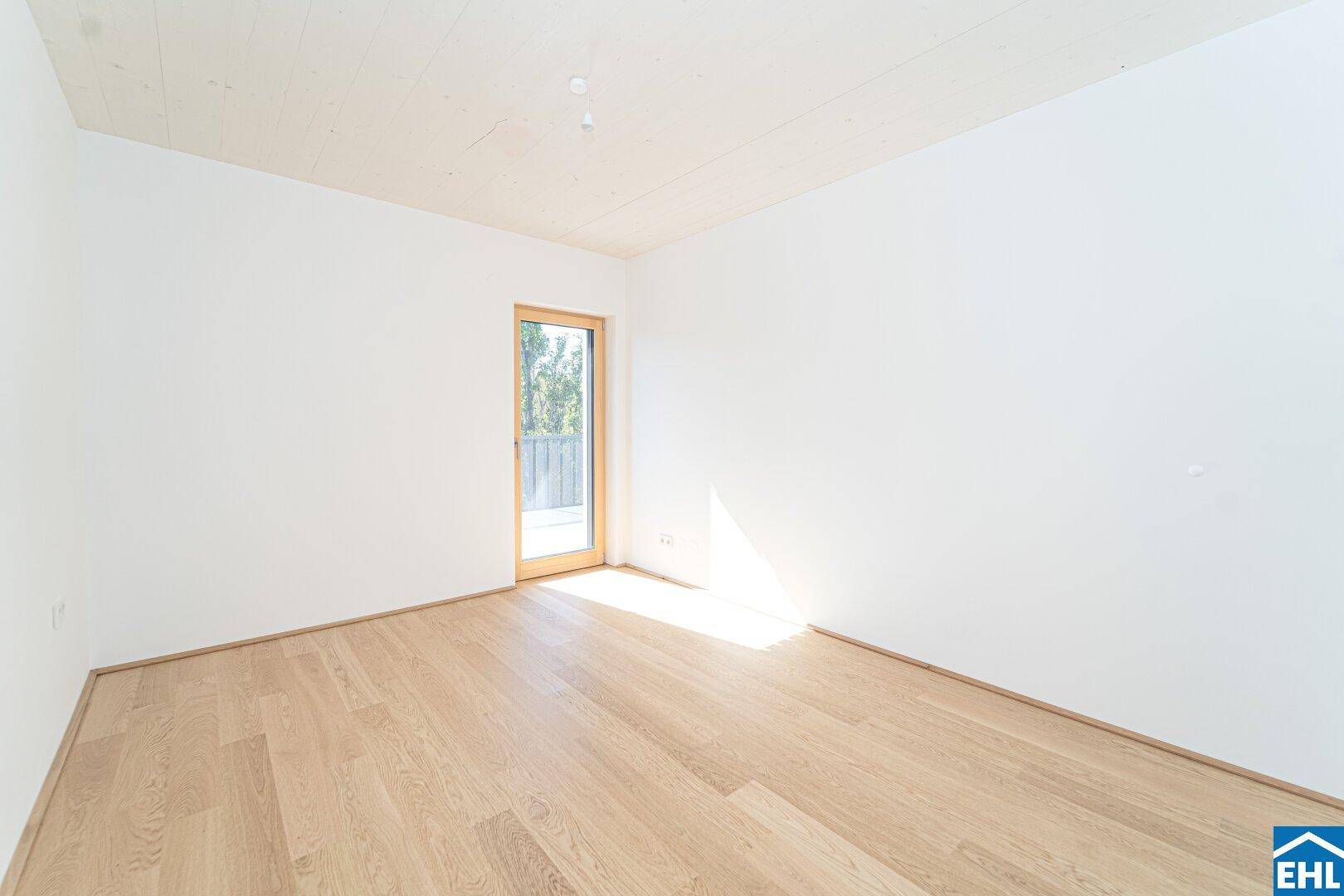 Freundliches Zimmer mit Holzboden und direktem Zugang zu einem Außenbereich.