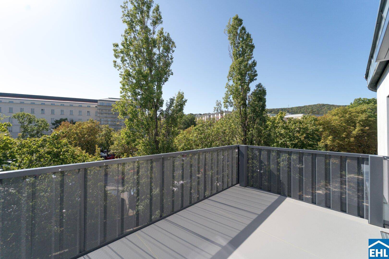Geräumiger Balkon mit Metallgeländer und weitem Blick ins Grüne und auf die Stadt.