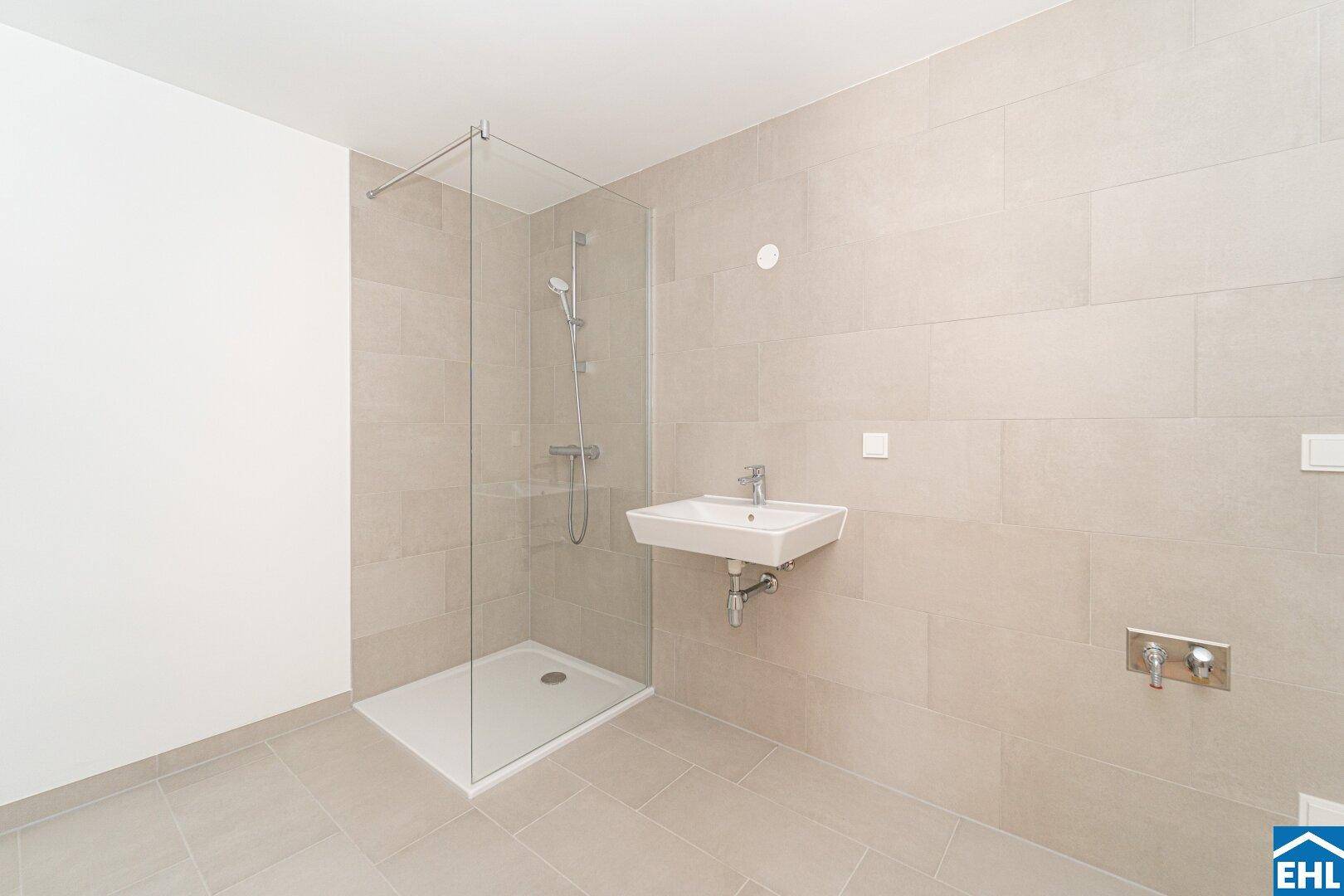 Modernes Badezimmer mit beigefarbenen Fliesen, ebenerdiger Dusche und Einzelwaschbecken.