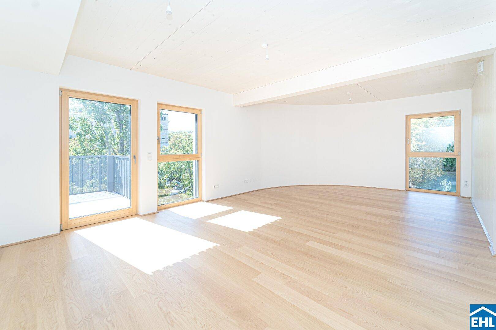 Helles Wohnzimmer mit Eichenparkett, großen Fenstern und Zugang zu einem Balkon.