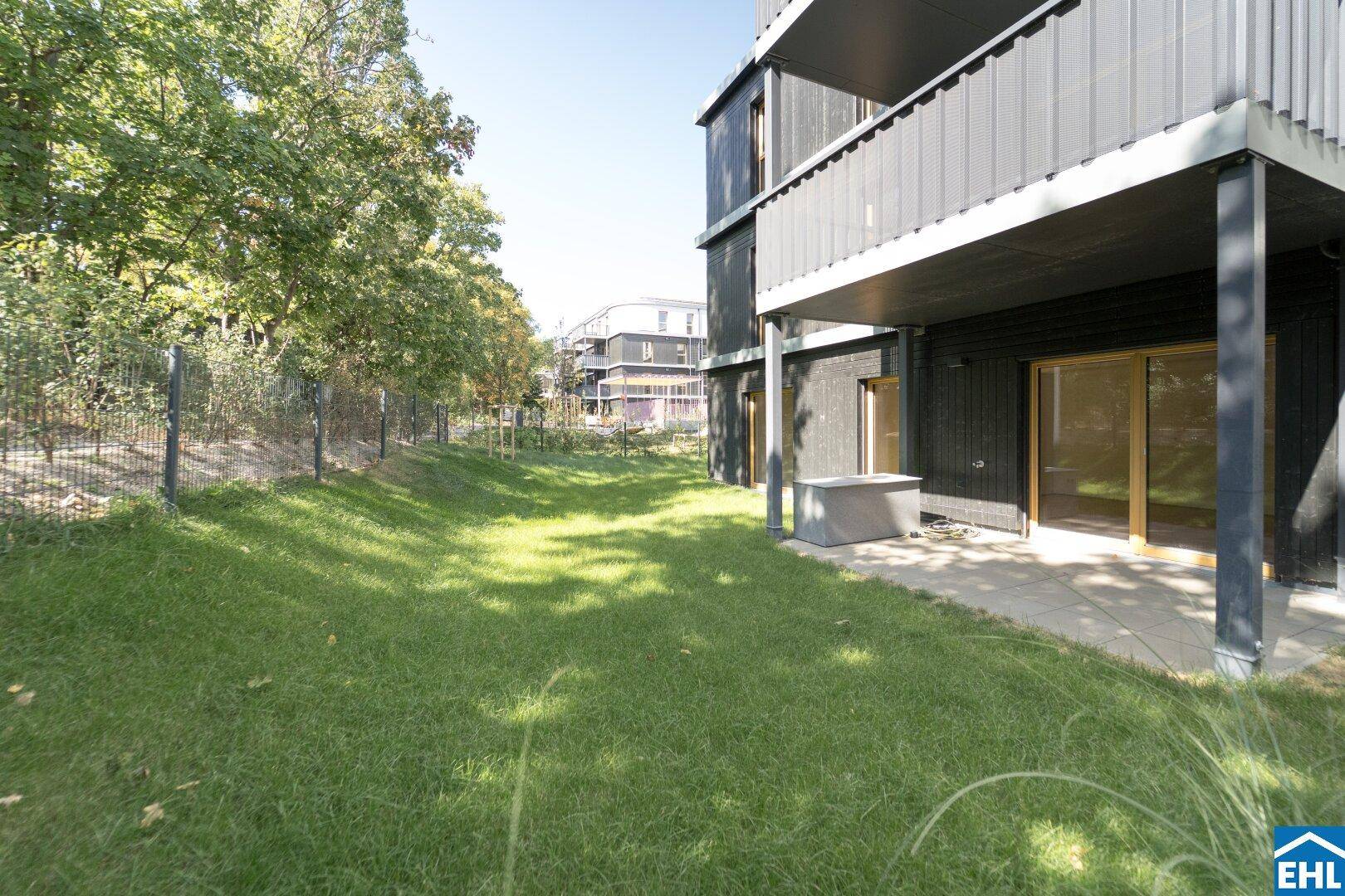 Weitläufiger Garten mit Rasenfläche und Zugang zu einer Terrasse am modernen Wohngebäude.