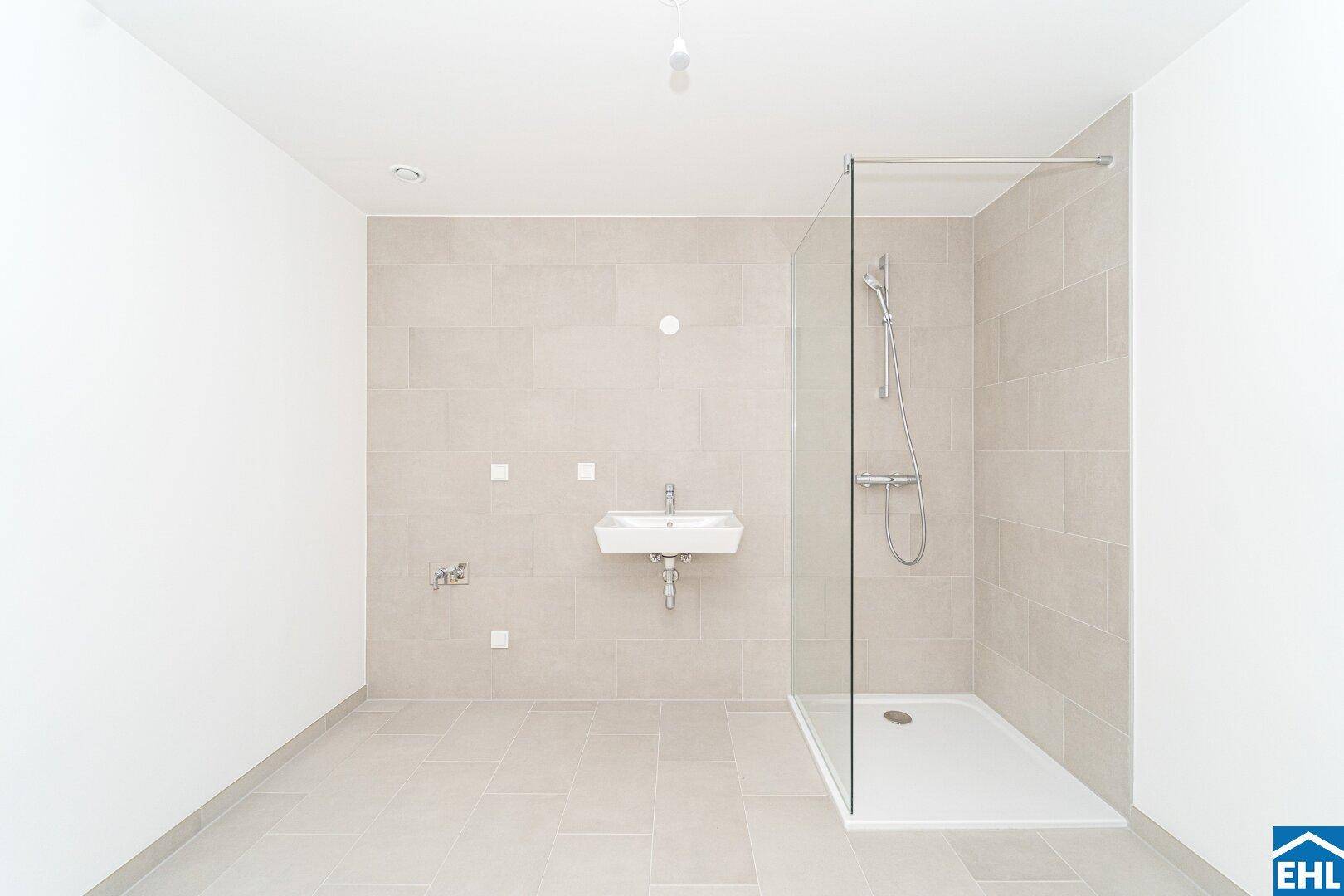 Modernes Badezimmer mit hellen Fliesen, ebenerdiger Dusche und Einzelwaschbecken.