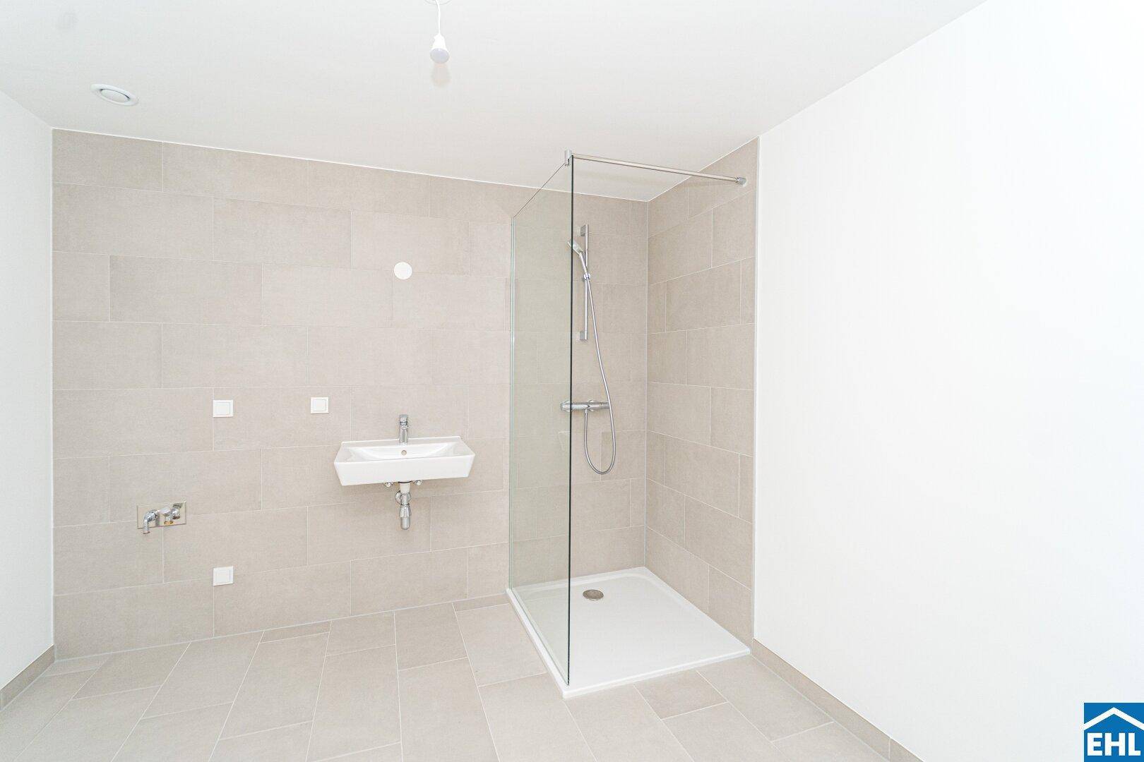Helles Badezimmer mit modernen Fliesen, Glasdusche und einem einzelnen Waschbecken.