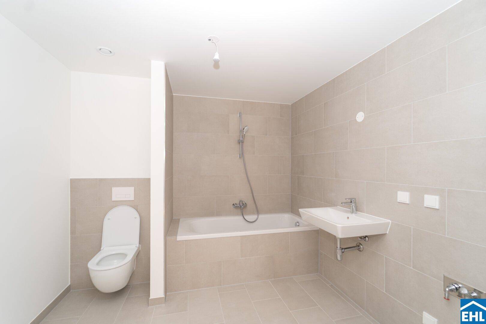 Zeitgemäßes Badezimmer mit Badewanne, wandhängendem WC und einem einzelnen Waschbecken.