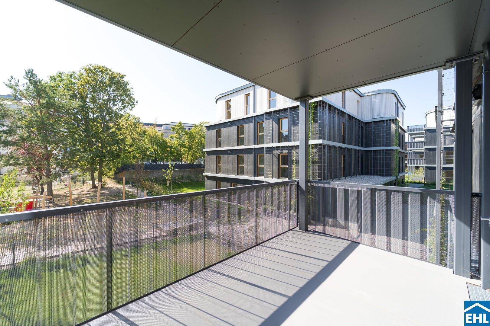 Geräumiger Balkon mit Blick auf die moderne Architektur des Gebäudes und die grüne Umgebung.
