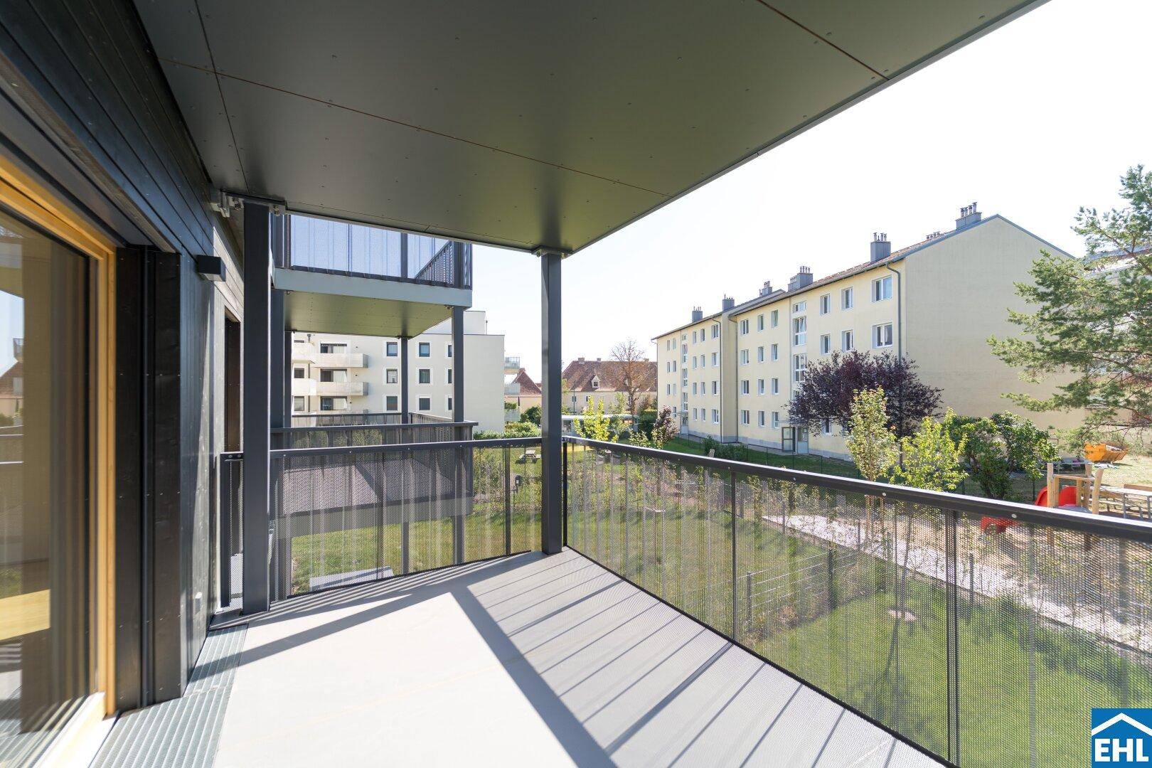Heller Balkon mit Ausblick auf die umliegenden Gebäude und eine gepflegte Grünfläche.