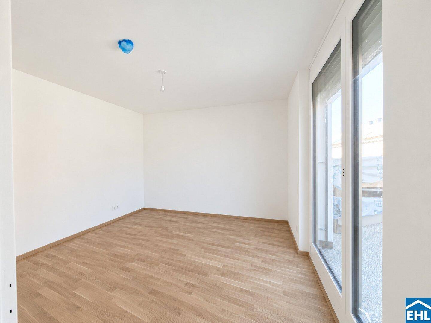 Helles Schlafzimmer mit Laminatboden und einem großen Fenster, das viel Tageslicht spendet.