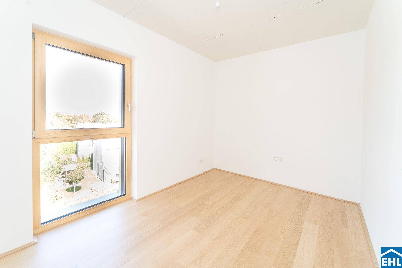 Geräumiges Schlafzimmer mit Parkettboden und einem Fenster mit Blick auf die Umgebung.