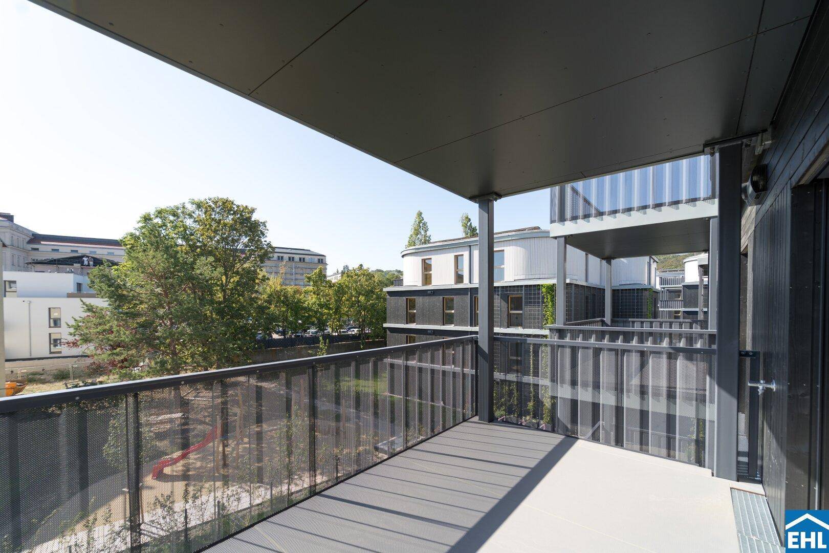Moderner Balkon mit Metallgeländer und Blick auf die umliegenden Gebäude und Grünflächen.