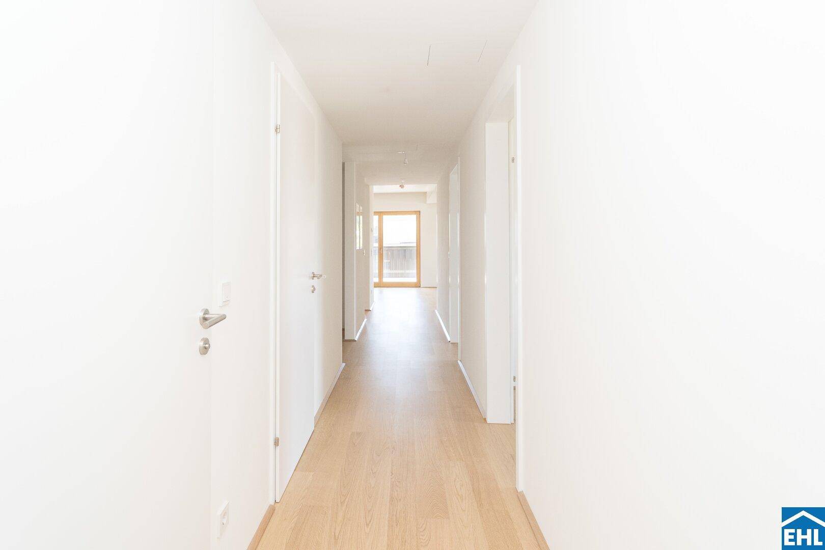 Langer, heller Flur mit Parkettboden, der die verschiedenen Räume der Wohnung verbindet.
