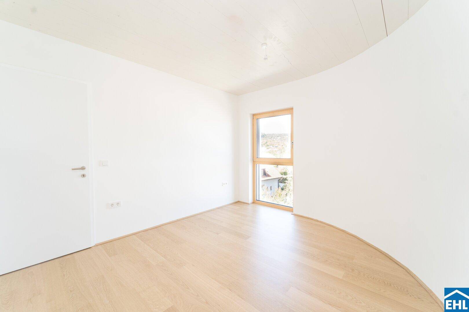 Helles Schlafzimmer mit Parkettboden und einer modernen, geschwungenen Wandgestaltung.