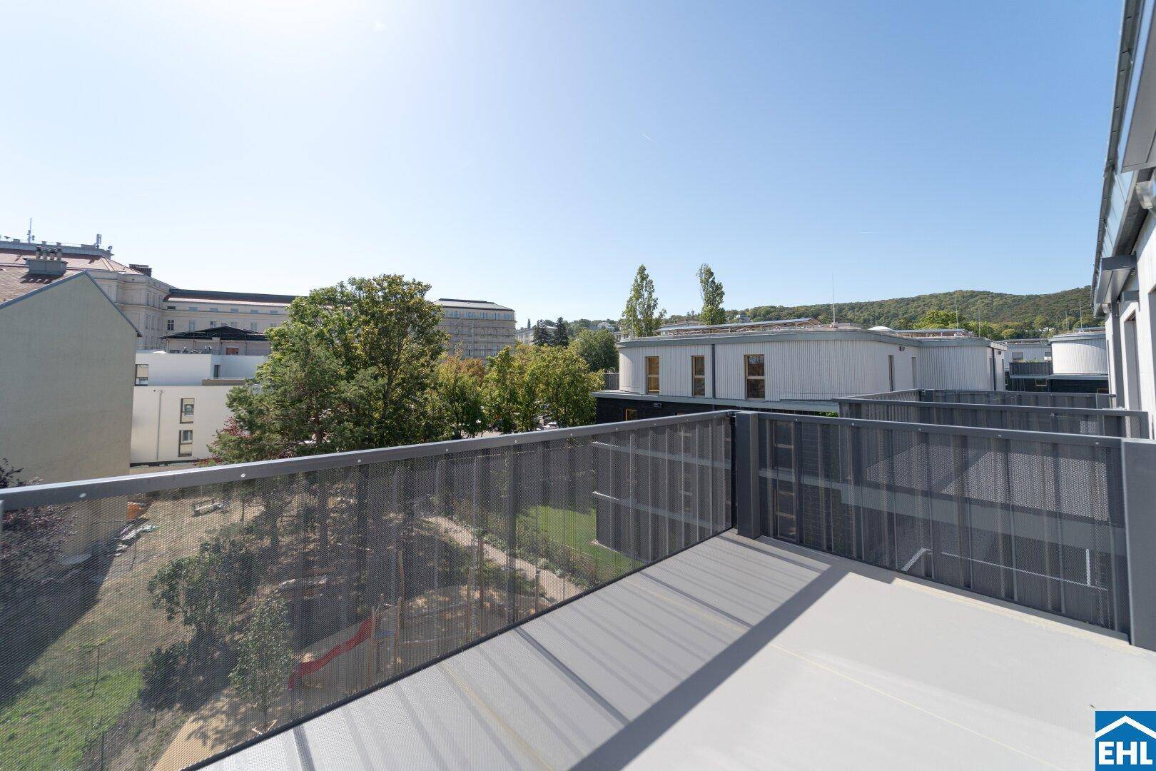 Geräumiger Balkon mit modernem Metallgeländer und Blick auf die umliegenden Gebäude und Grünflächen.
