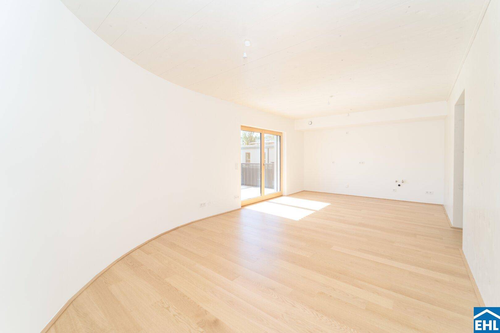 Geräumiger, lichtdurchfluteter Wohnbereich mit hellem Holzparkett und Zugang zur Terrasse oder Balkon.