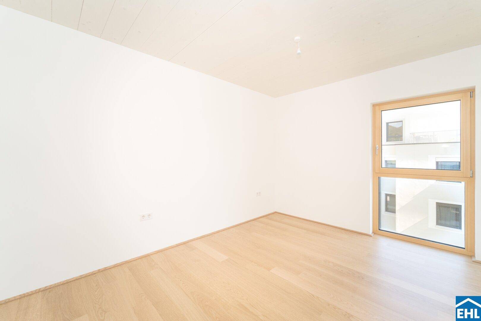 Helles Zimmer mit Eichenparkett und einem hohen Fenster, das für gute Belichtung sorgt.