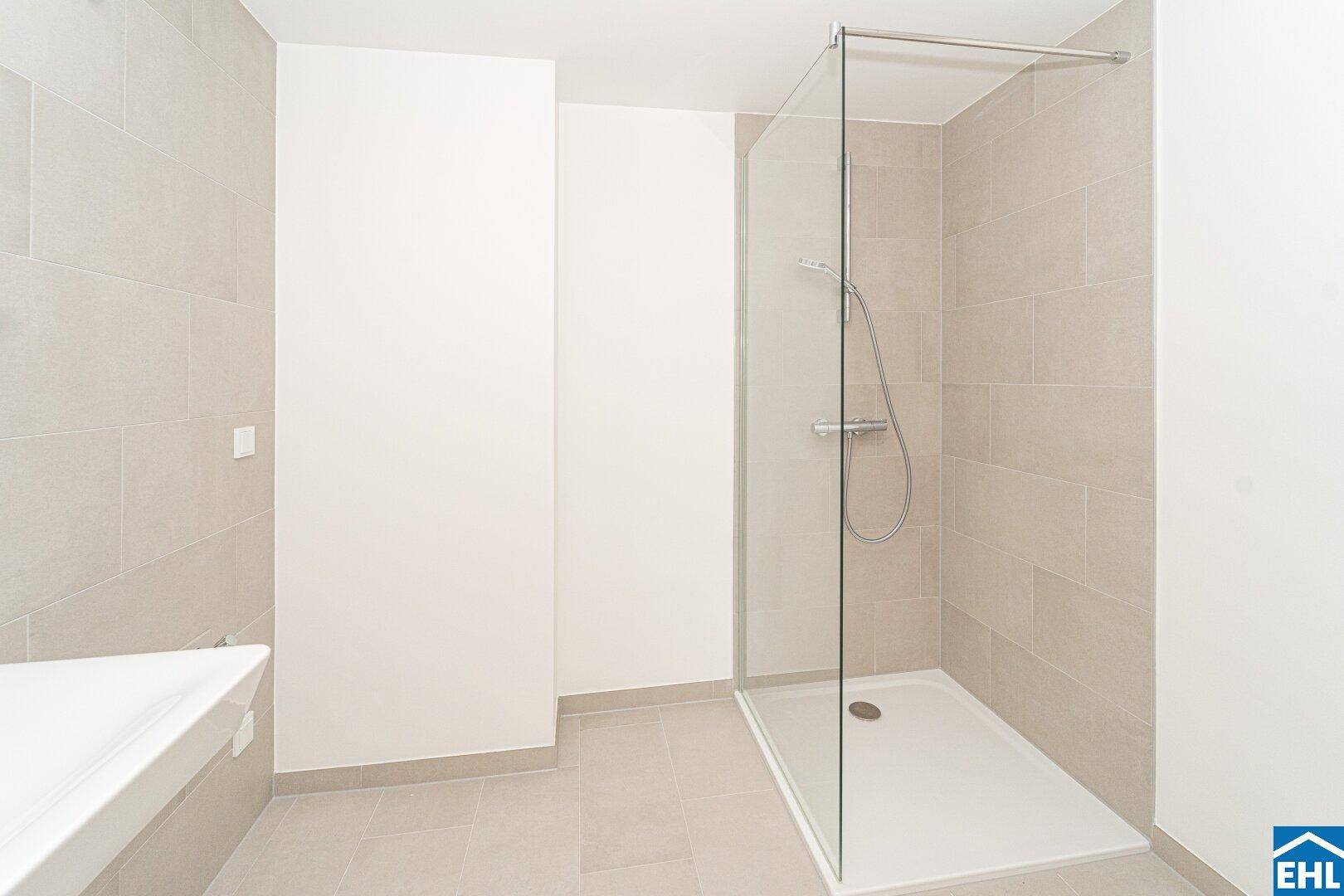 Modernes Badezimmer mit hellgrauen Fliesen und einer geräumigen, ebenerdigen Dusche mit Glaswand.