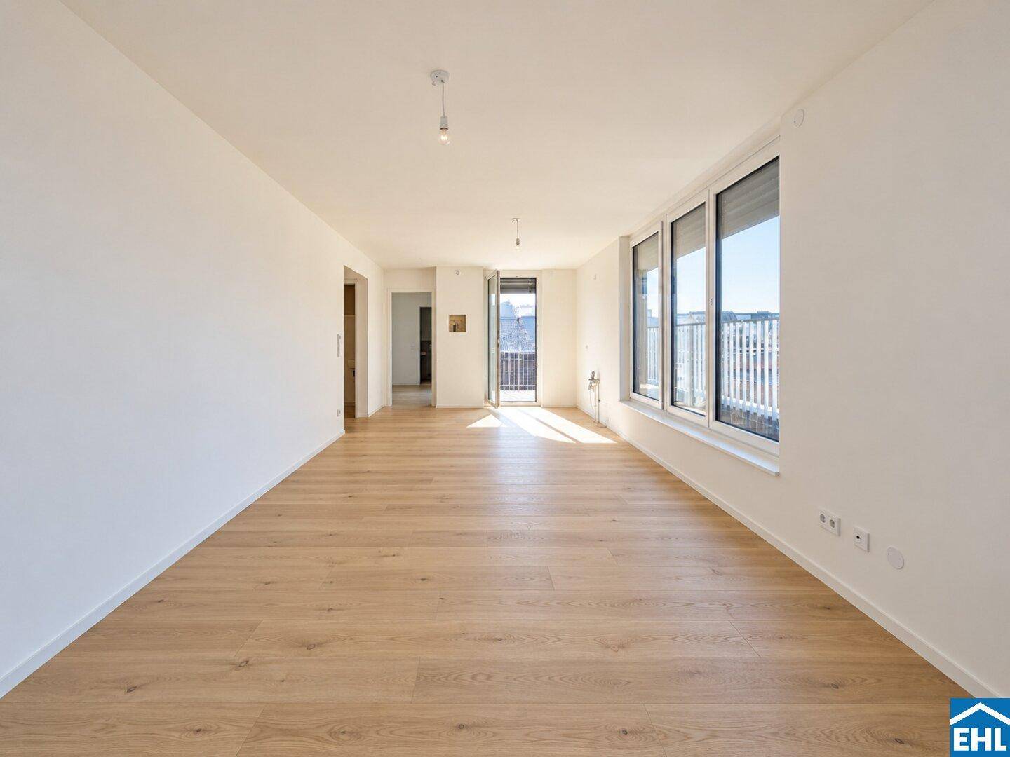 Geräumiges, helles Wohnzimmer mit Holzboden und Zugang zu einem Balkon.