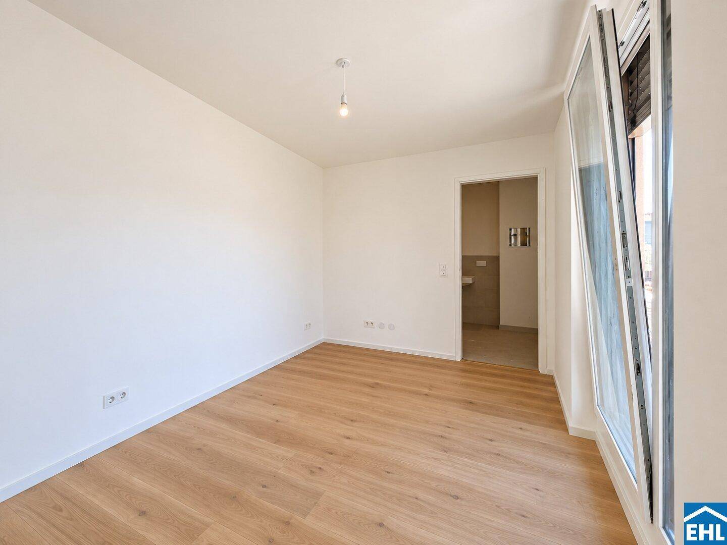 Helles Zimmer mit Parkettboden und großem Fenster, ideal als Schlaf- oder Arbeitszimmer.