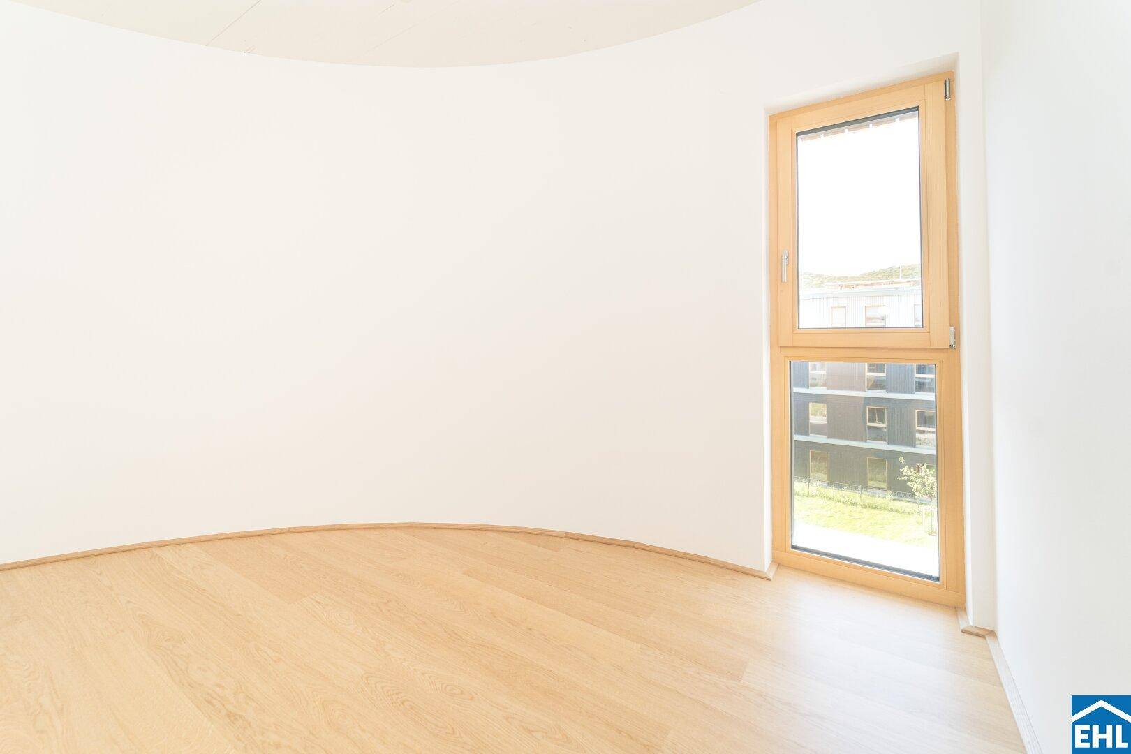 Modernes Schlafzimmer mit geschwungener Wand, hellem Parkett und Blick auf die Umgebung.