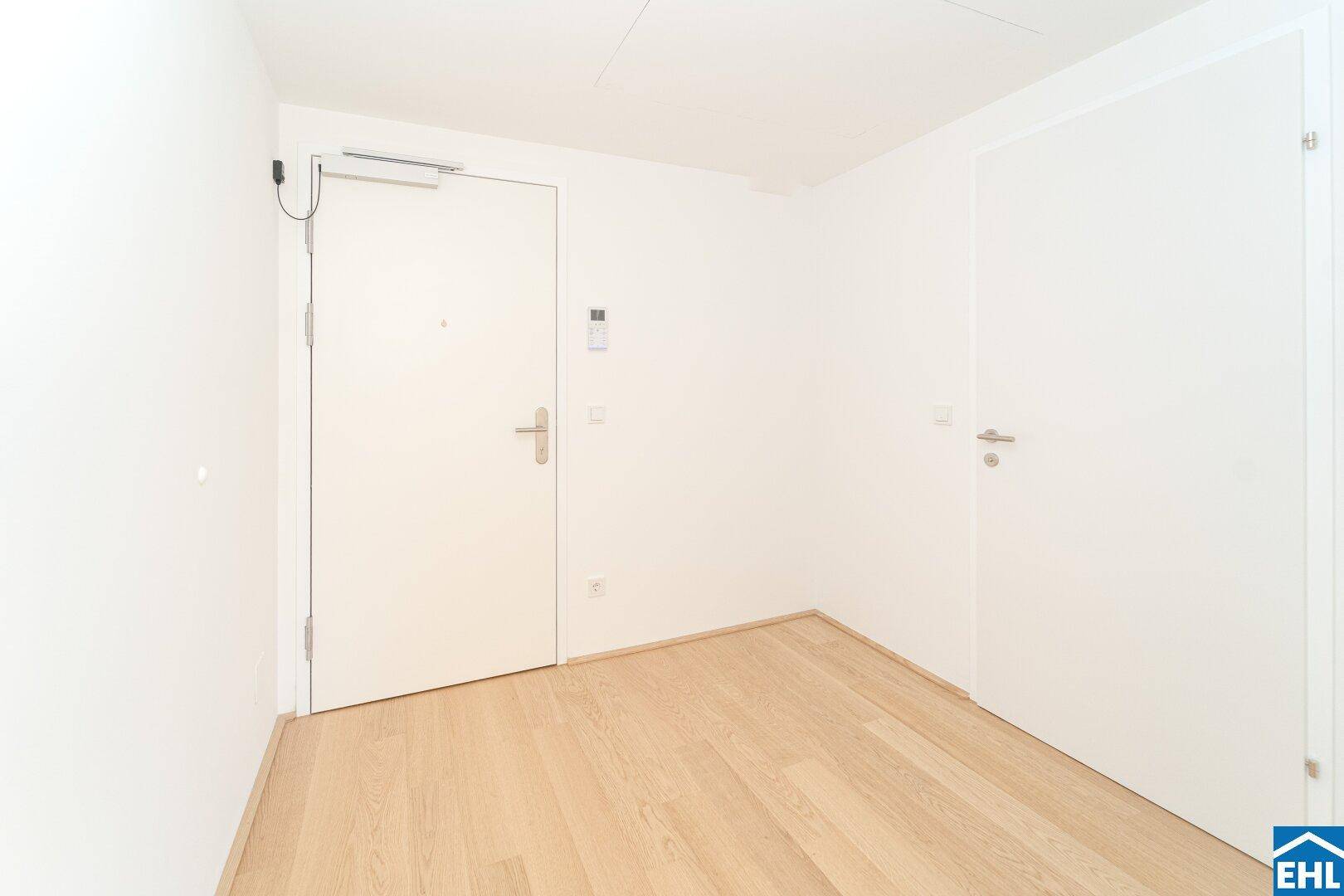 Heller Eingangsbereich mit Holzboden und zwei weißen Türen, bereit für die individuelle Gestaltung.