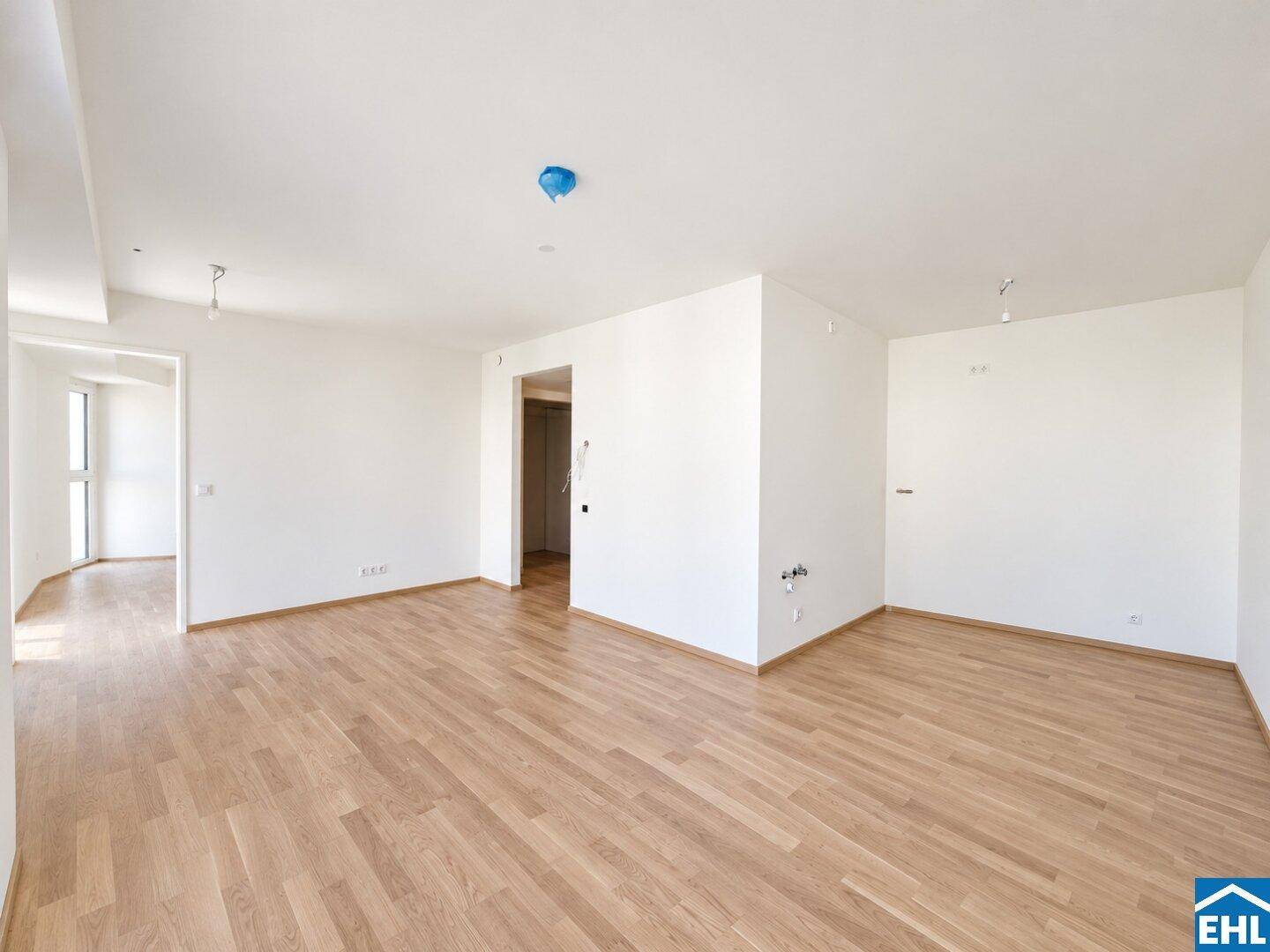 Geräumiges, leeres Zimmer mit hellem Holzboden und weißen Wänden, bereit zur Einrichtung.