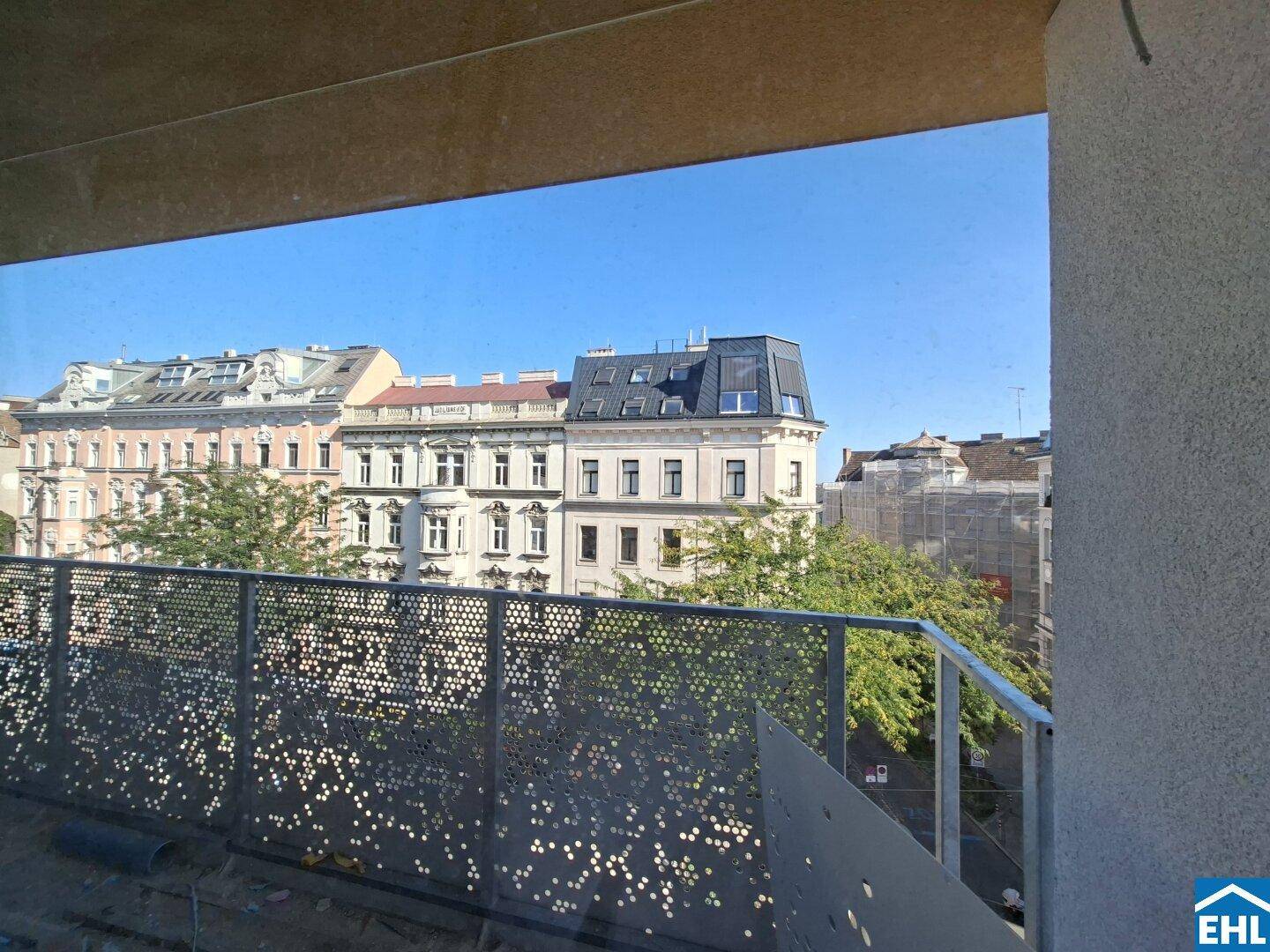 Blick vom Balkon auf die umliegenden Gebäude und die Stadtlandschaft unter blauem Himmel.