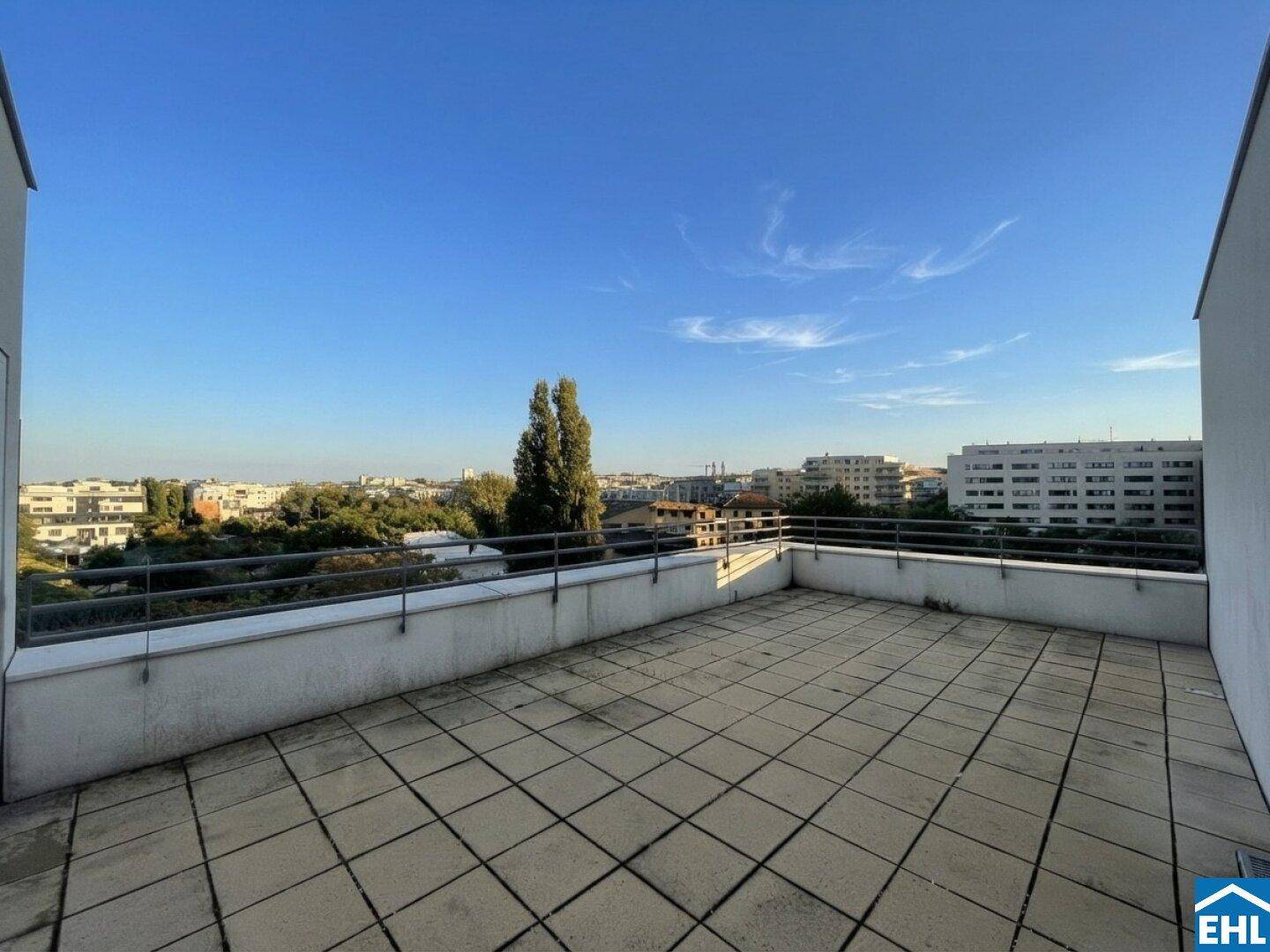 Geräumige Dachterrasse mit weitem Blick über die Stadt und umliegende Grünflächen.