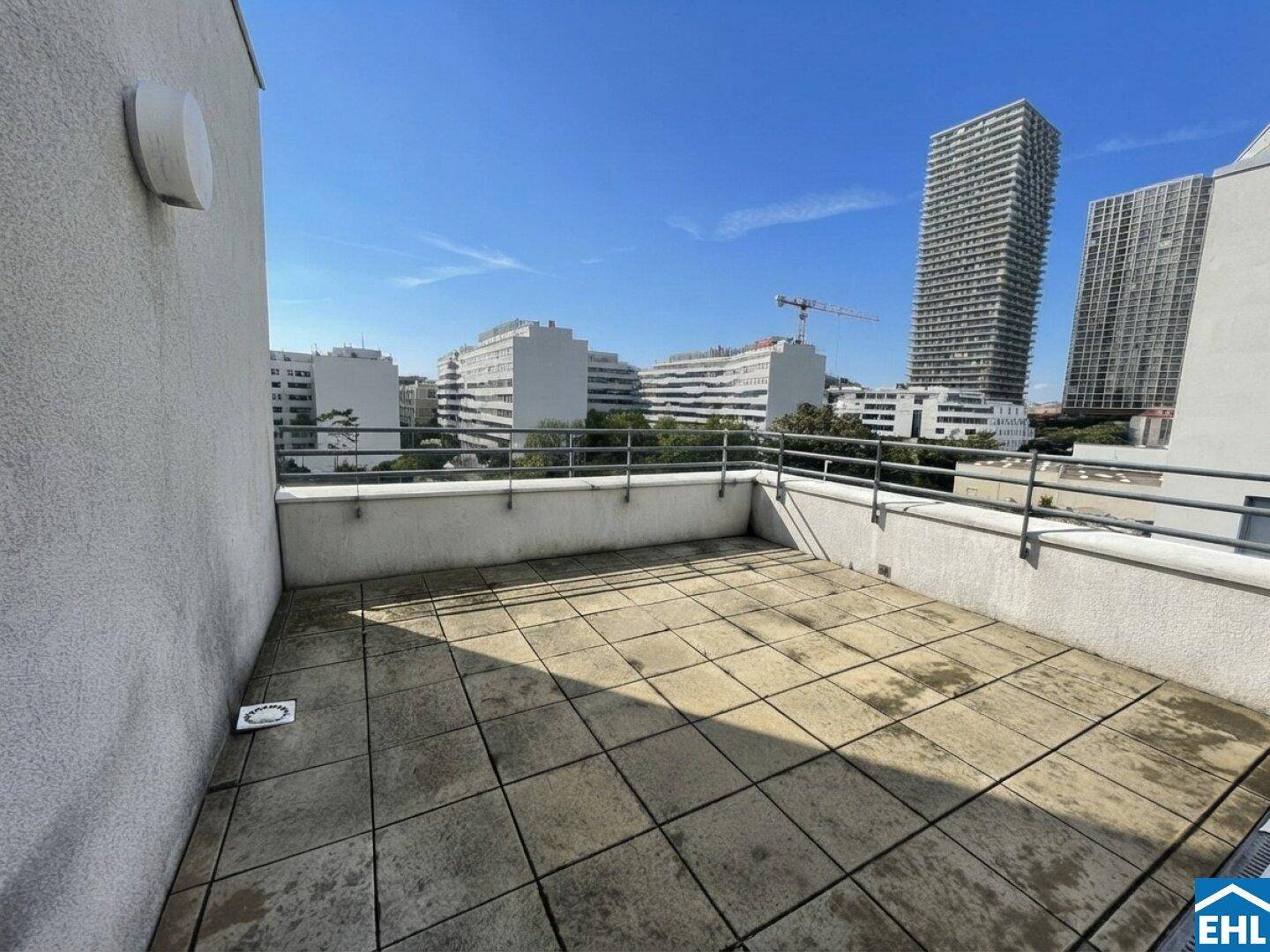 Geräumige Terrasse mit Stadtblick und modernen Hochhäusern im Hintergrund.