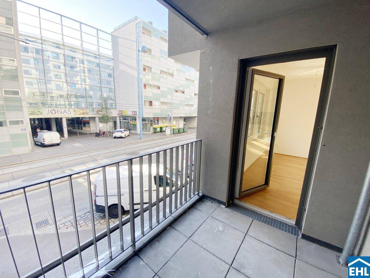 Balkon mit Blick auf die belebte Stadtstraße und umliegende Gebäude.