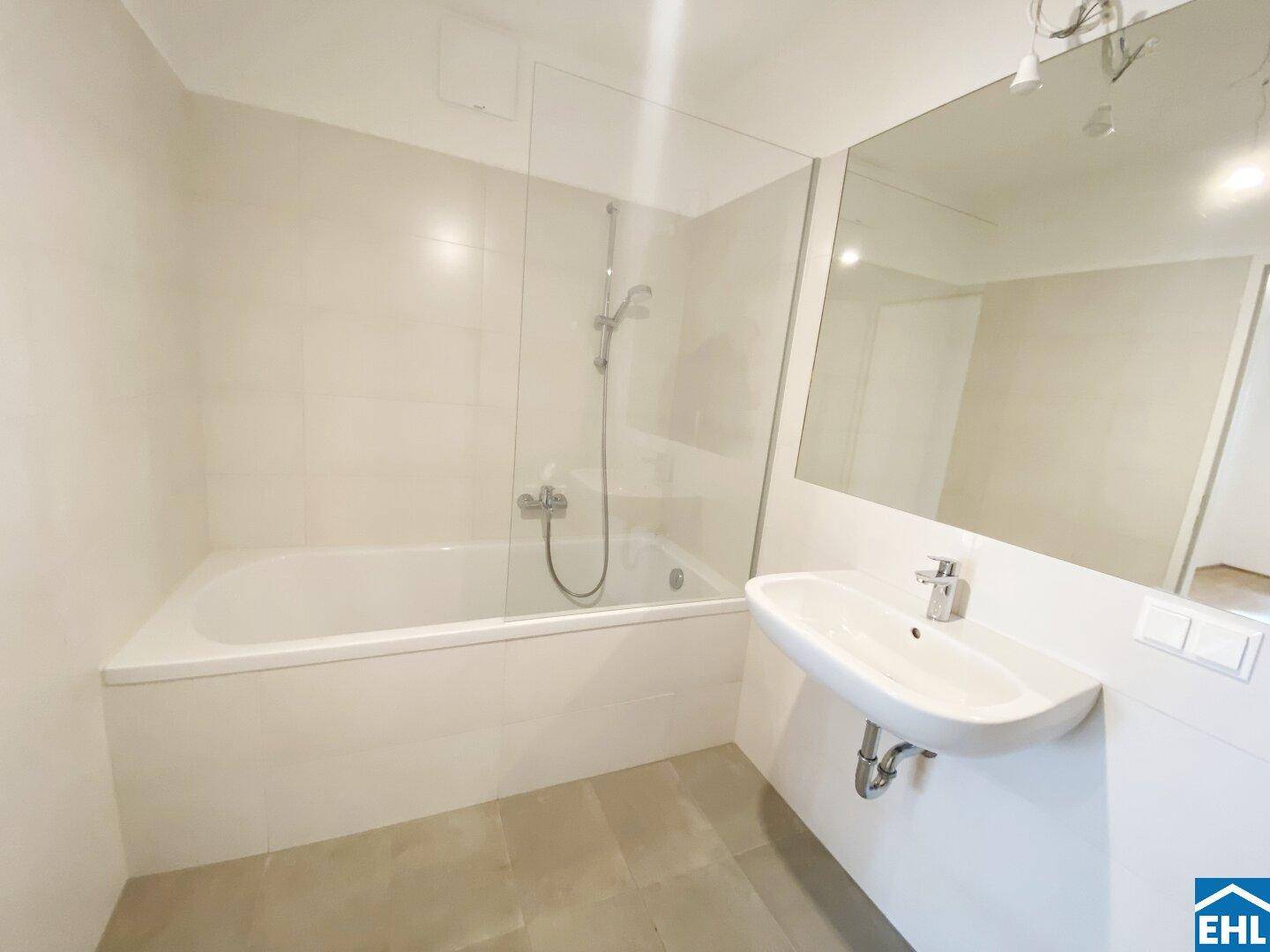 Modernes Badezimmer mit Badewanne, Waschbecken und großem Spiegel.