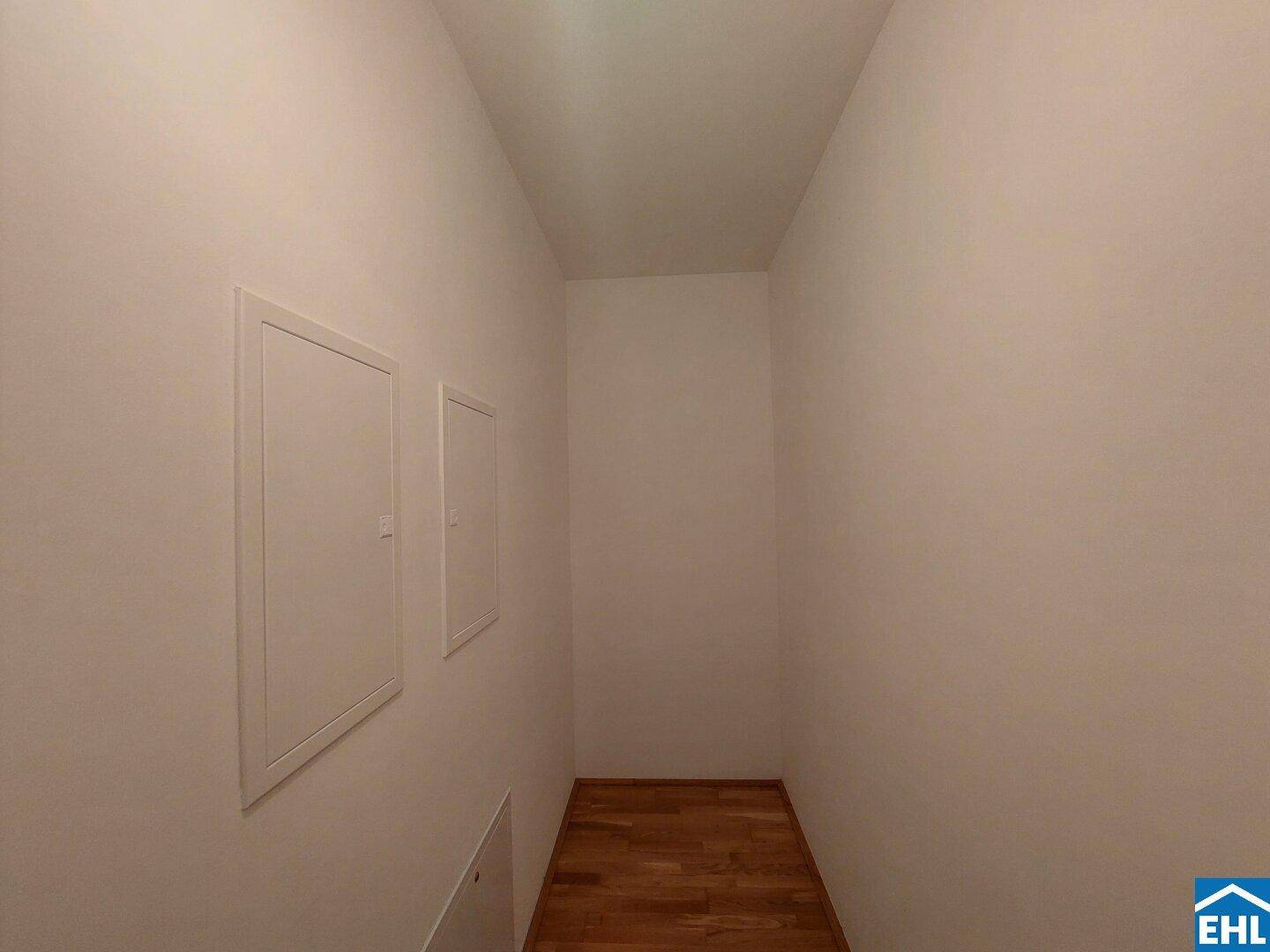 Schmaler Flur mit Parkettboden und weißen Wänden, ideal als Abstellraum nutzbar.