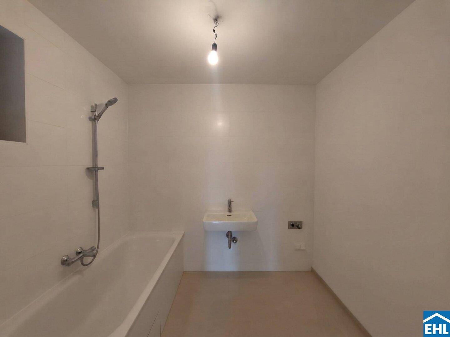 Modern gefliestes Badezimmer mit Badewanne und Waschbecken in neutralen Farbtönen.
