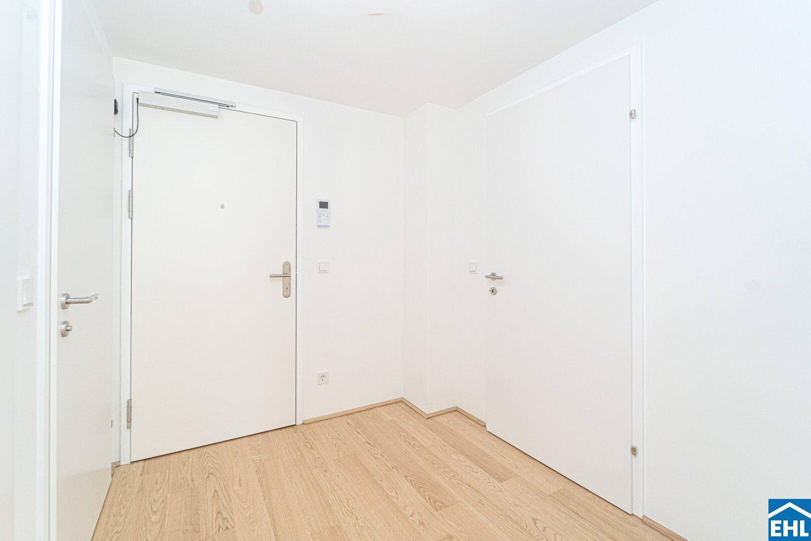 Heller Eingangsbereich mit Holzboden und mehreren Türen, der zu den verschiedenen Räumen führt.