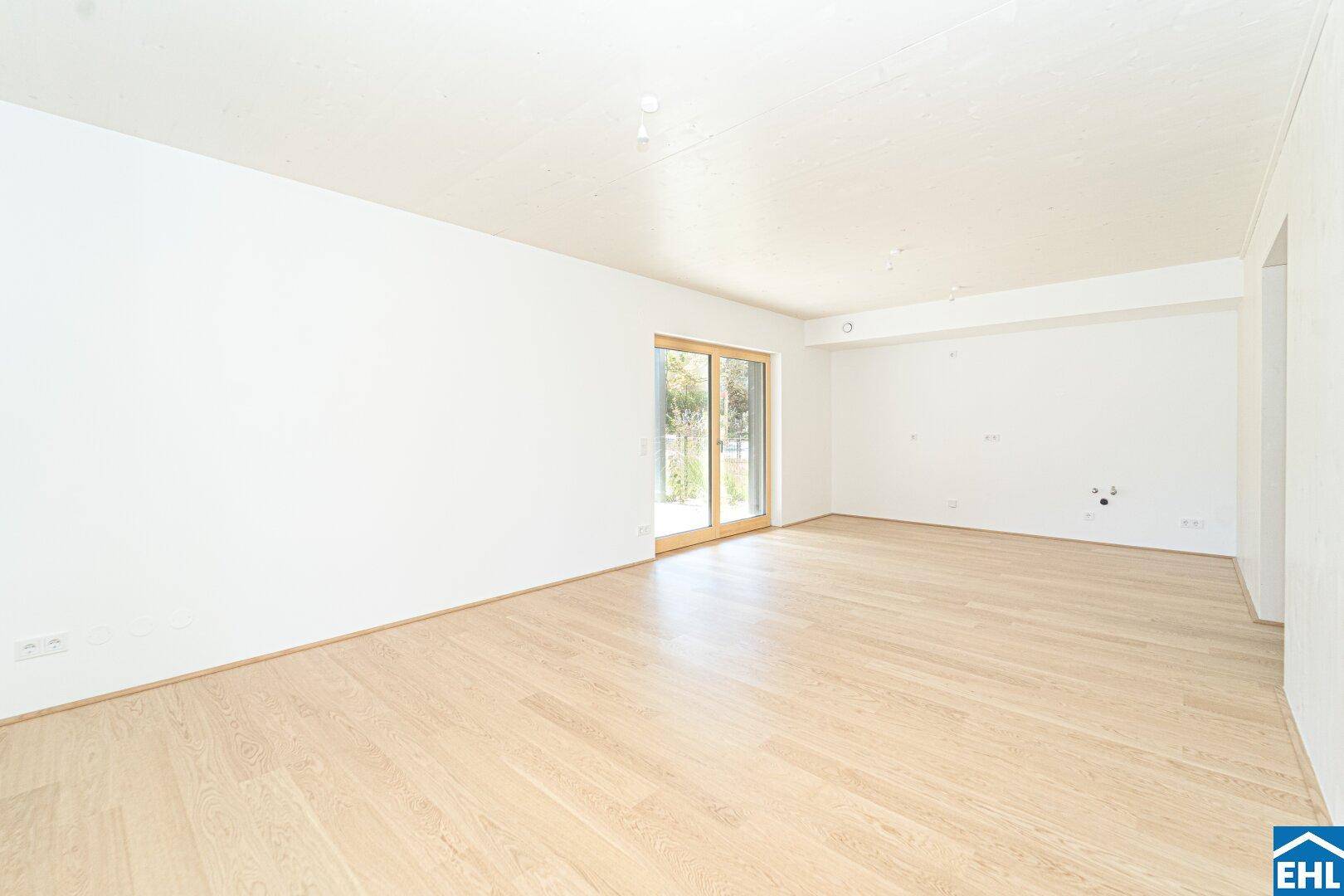 Geräumiges, helles Zimmer mit Parkettboden und Vorbereitung für eine Küche.