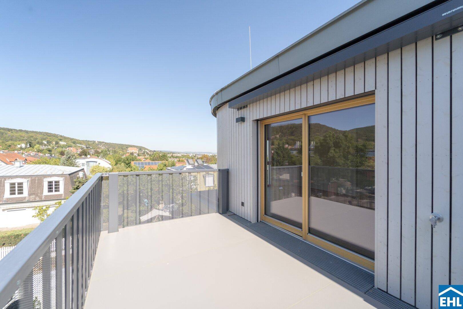 Moderner Balkon mit Schiebetür und Holzverkleidung, bietet einen weiten Blick in die Umgebung.