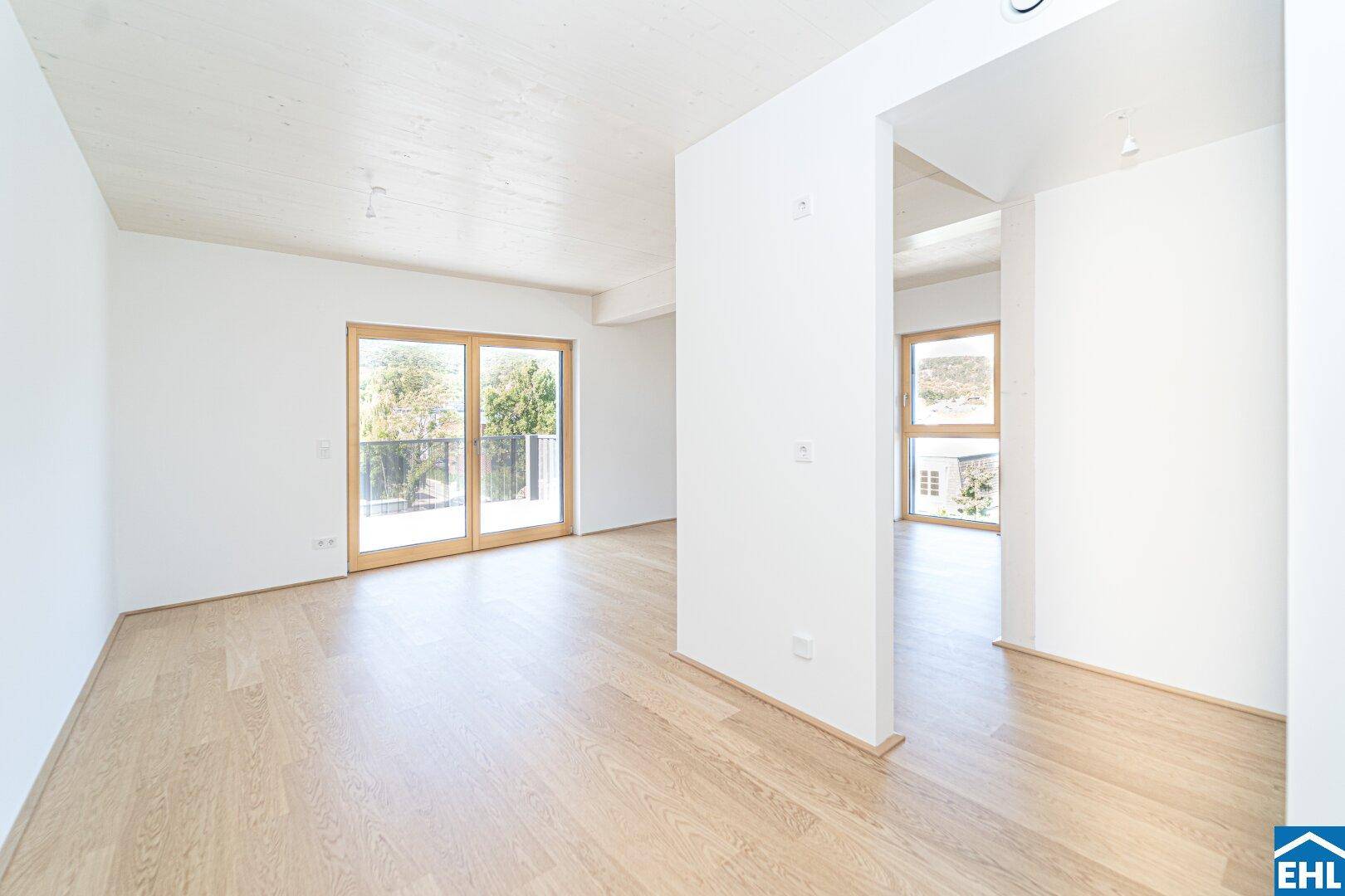 Geräumiger, heller Wohnbereich mit Holzboden und großen Schiebetüren, die viel Tageslicht hereinlassen.
