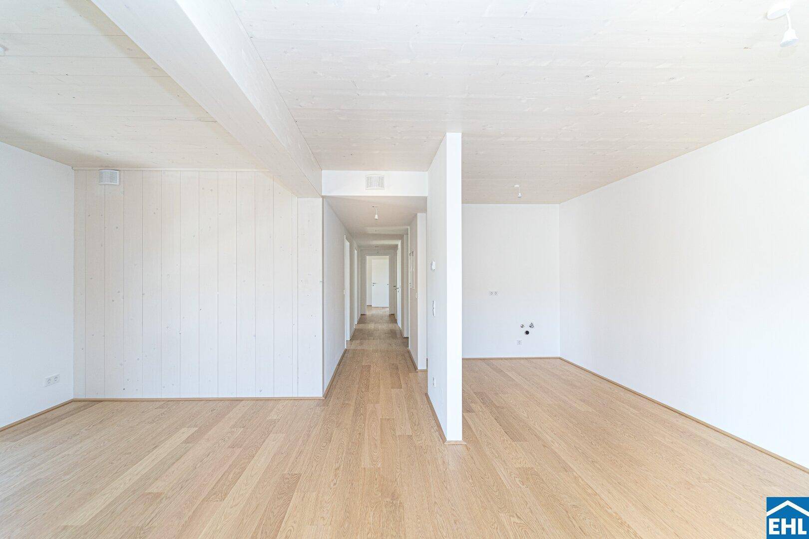 Langer, heller Flur mit Holzboden und weißen Wänden, der verschiedene Wohnbereiche verbindet.