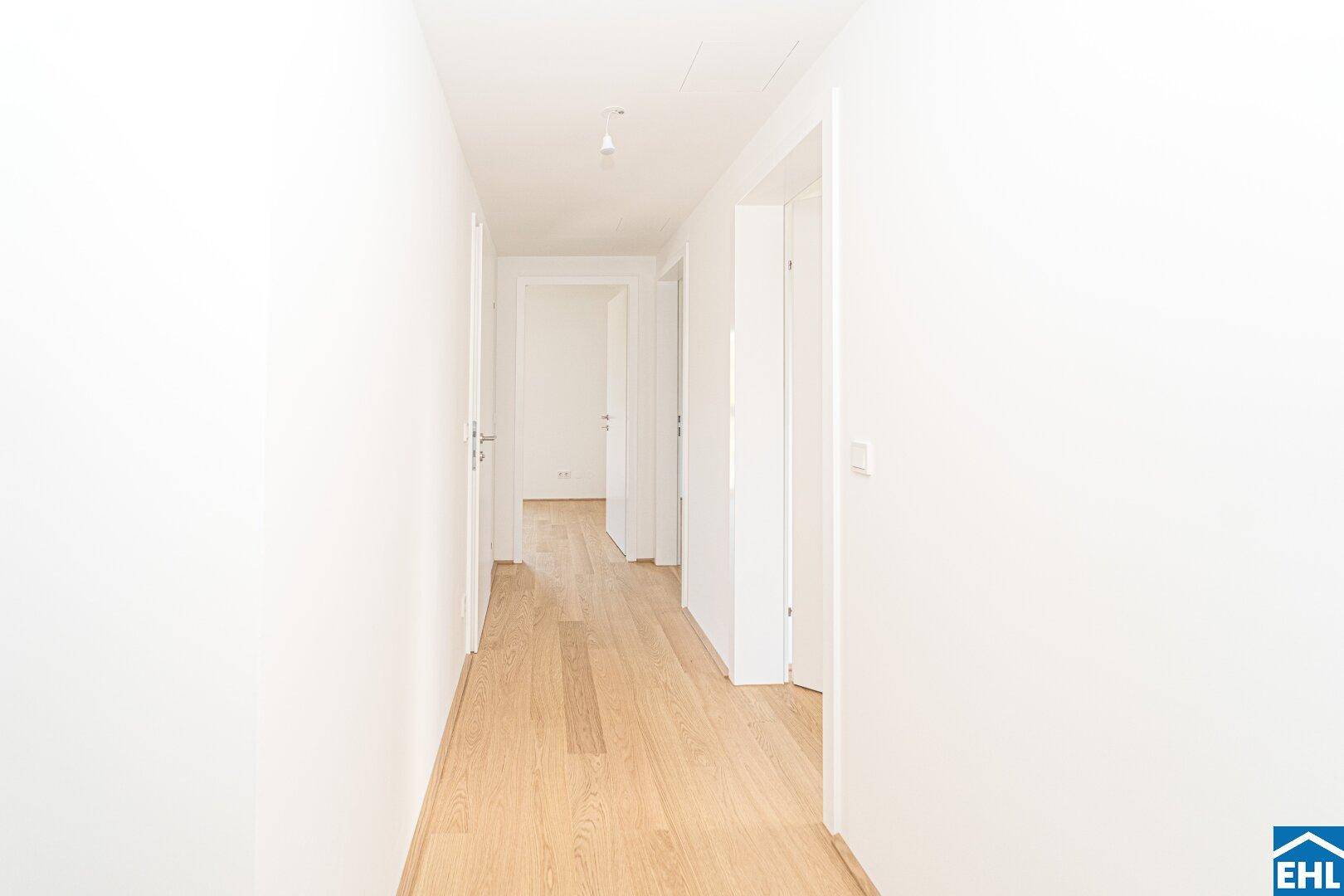 Heller Flur mit hellem Holzfußboden, der zu weiteren Räumen der Wohnung führt.