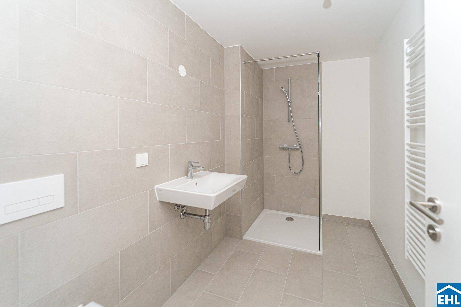 Modernes Badezimmer mit hellgrauen Fliesen, ebenerdiger Dusche und praktischem Handtuchheizkörper.