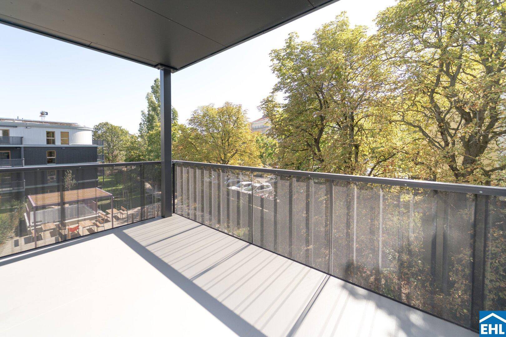 Heller Balkon mit Blick auf Bäume und einen Spielplatz im Innenhof, perfekt für Familien.