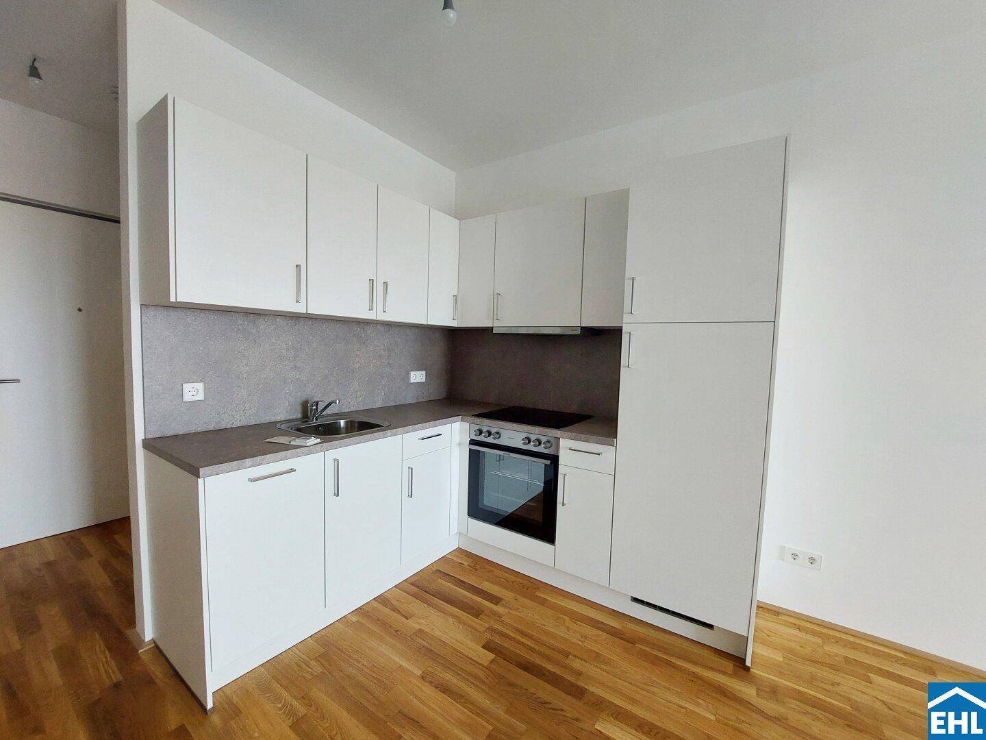Moderne Küchenzeile mit weißen Schränken, integriertem Backofen und Kochfeld.