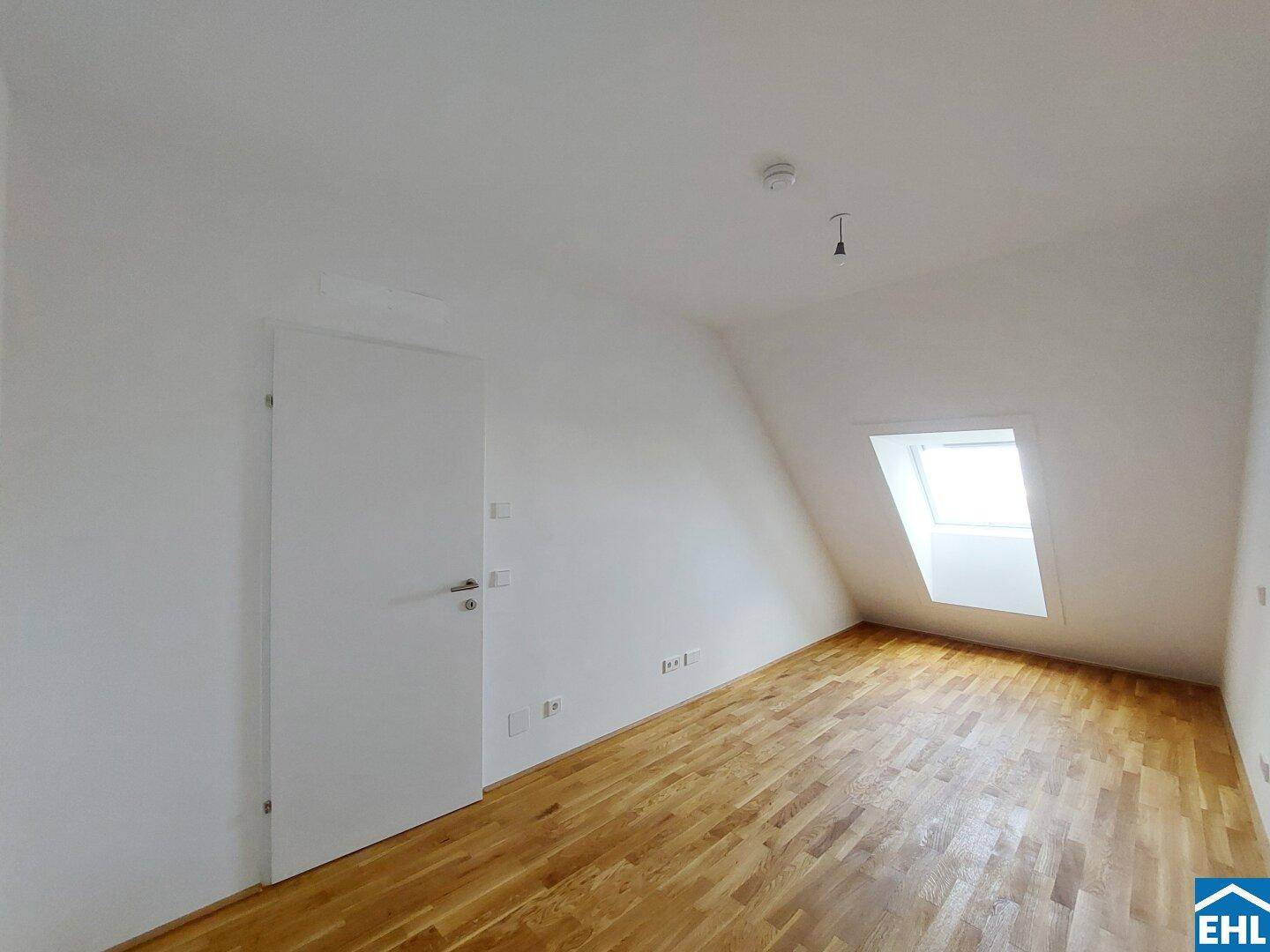 Helles Schlafzimmer im Dachgeschoss mit Holzboden und Dachfenster für viel Tageslicht.