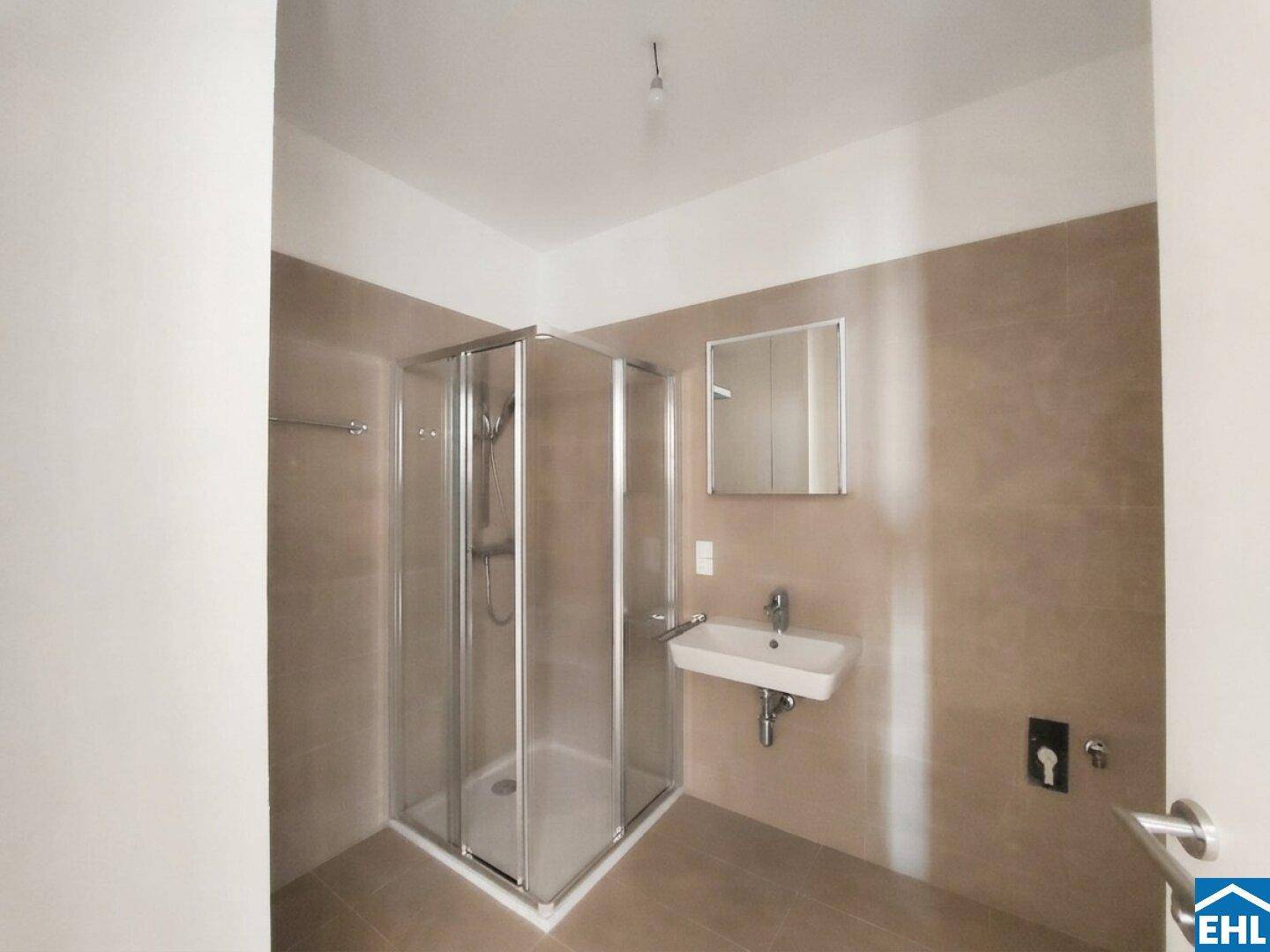 Modernes Badezimmer mit Duschkabine, Waschbecken und beigefarbenen Fliesen.