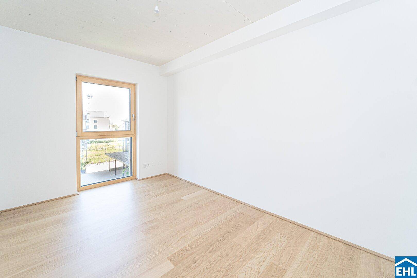 Geräumiges Schlafzimmer mit hellem Holzboden und einem großen Fenster für viel Tageslicht.