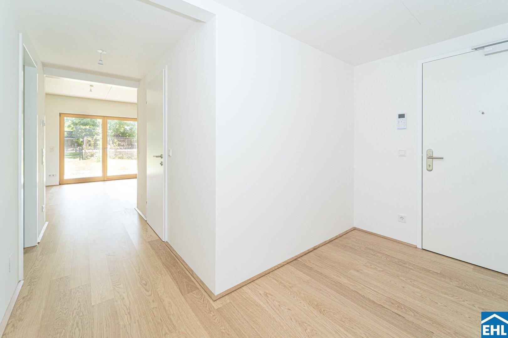 Heller Flur mit Parkettboden, weißen Wänden und Blick in den Wohnbereich.