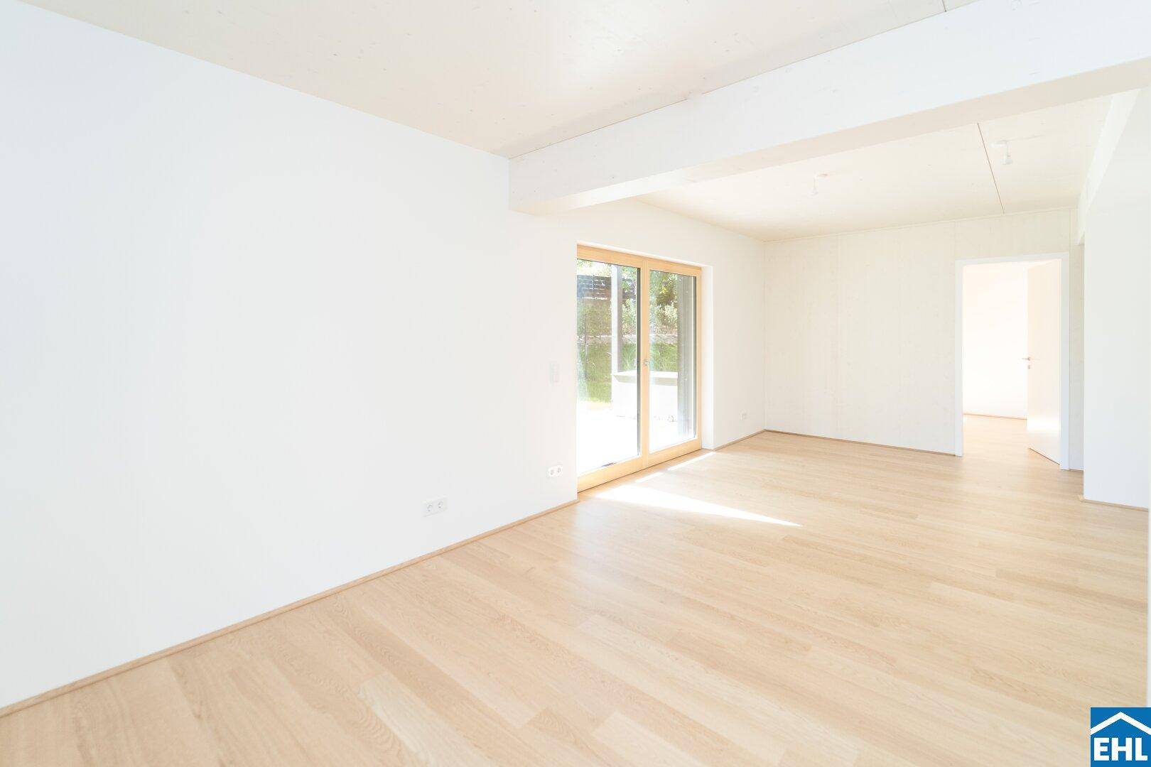 Geräumiges Wohnzimmer mit Holzboden und einer großen Schiebetür, die zum Garten führt.