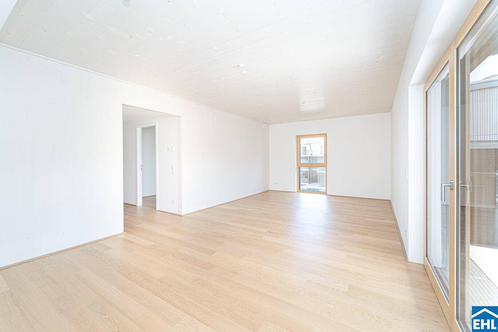 Geräumiges, unmöbliertes Wohnzimmer mit Holzboden und großen Fenstern, bereit zur Einrichtung.